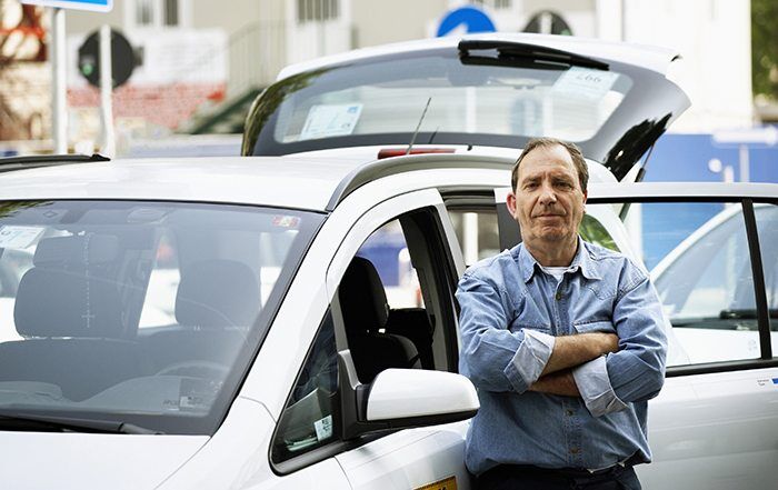 Driver standing in front of his car