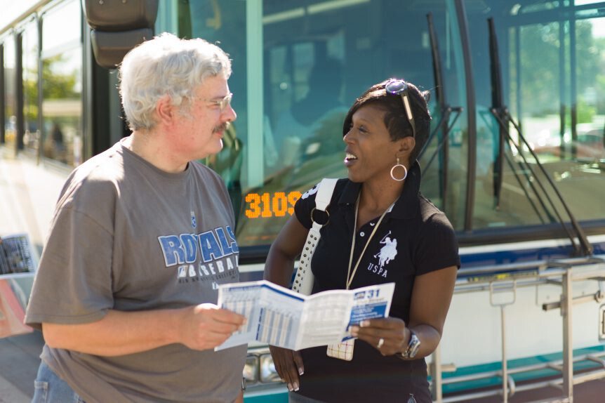 Travel trainer helping man navigate the local transit map