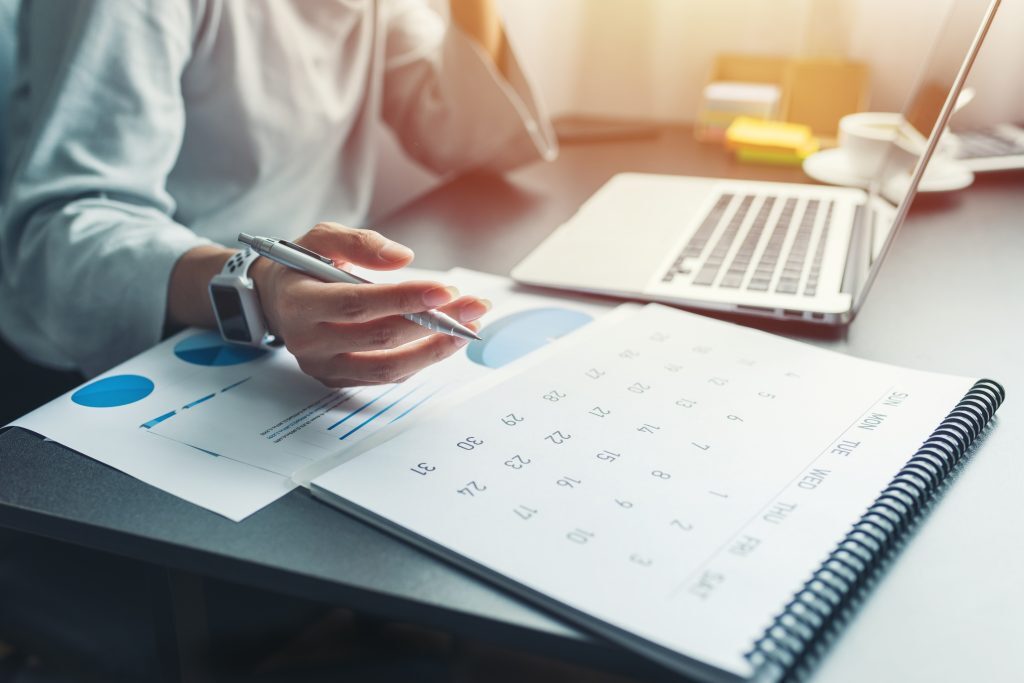 Business woman sitting working and thinking to plan event with calendar and laptop