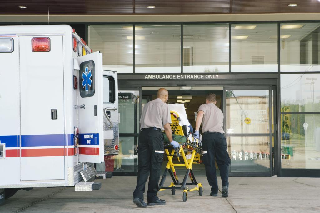 Two EMS workers exit their ambulance and wheel a patient into the ER. Access to NEMT results in better health outcomes and appropriate ER diversion.