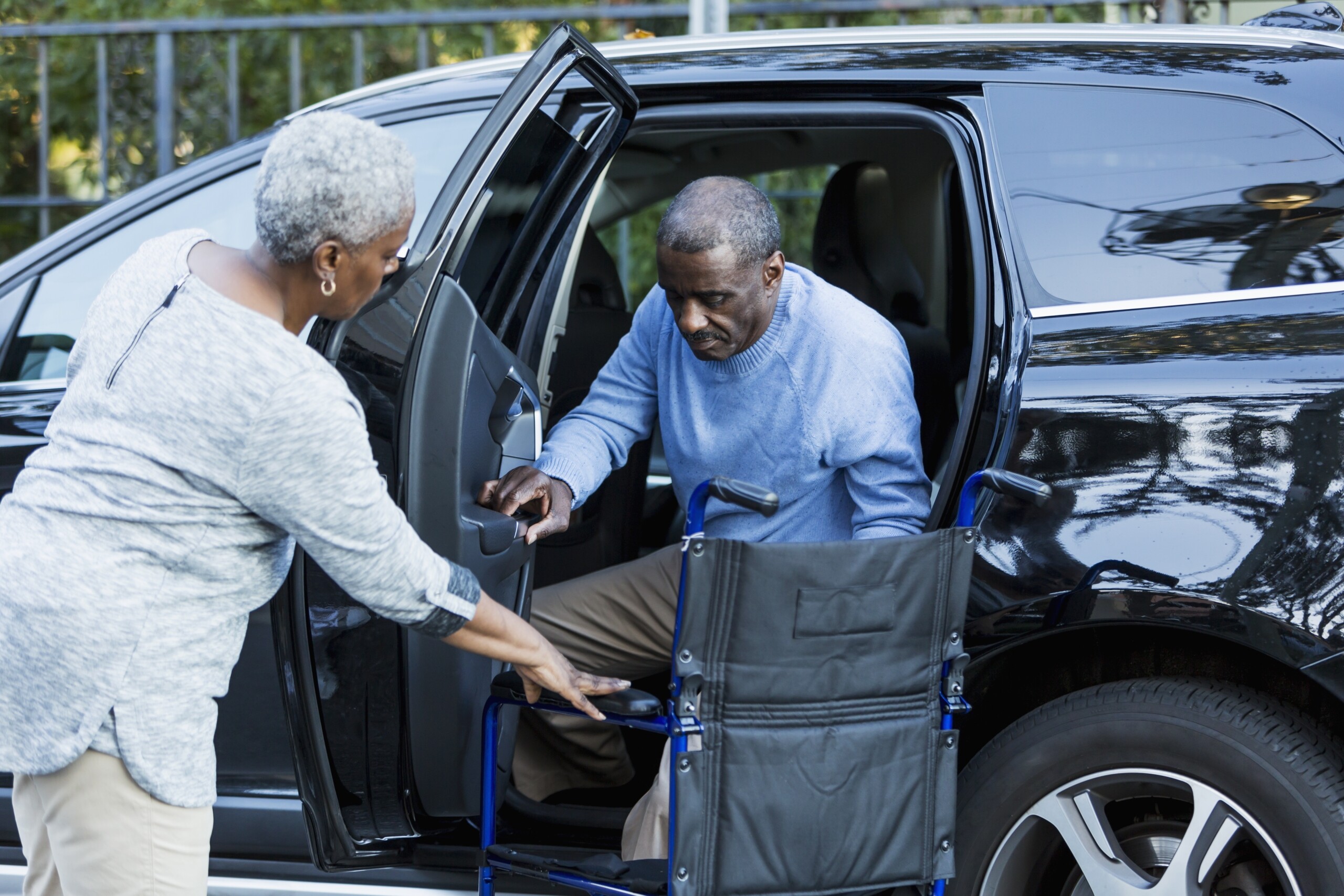 Disabled senior man getting from car to wheelchair